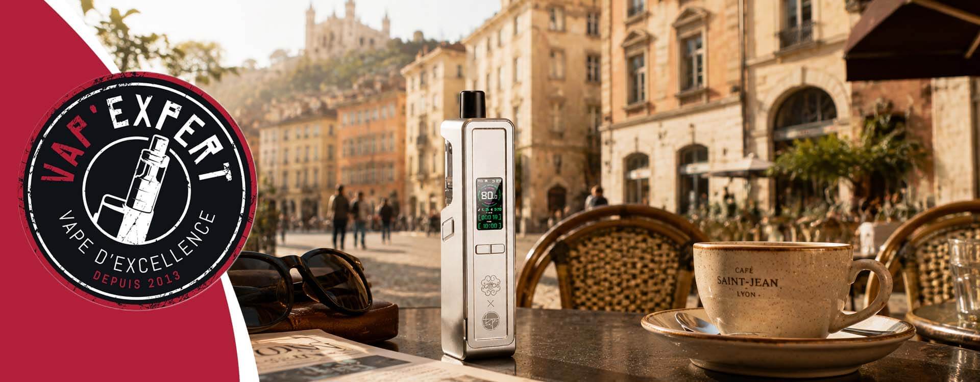 Cette image repr&eacute;sente la DotAMP de DotMod sur une table de caf&eacute; &agrave; Lyon, disponible chez Vap'Expert.